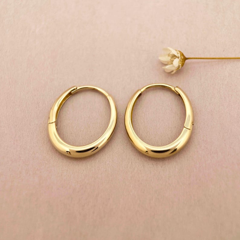 May include: A pair of gold hoop earrings. The earrings are simple and classic, with a smooth, polished finish.