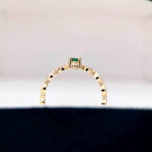 Puede incluir: Un anillo de oro con una banda texturizada y una peque&ntilde;a piedra preciosa verde.