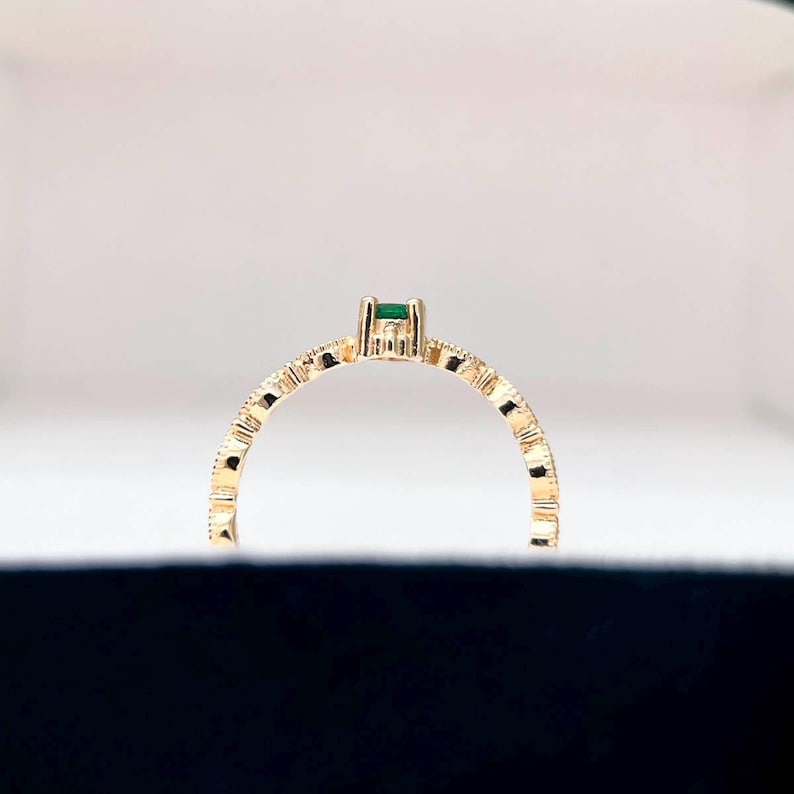 Puede incluir: Un anillo de oro con una banda texturizada y una peque&ntilde;a piedra preciosa verde.
