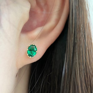 Puede incluir: Un par de pendientes de oro con una piedra preciosa verde en un engaste de corona.