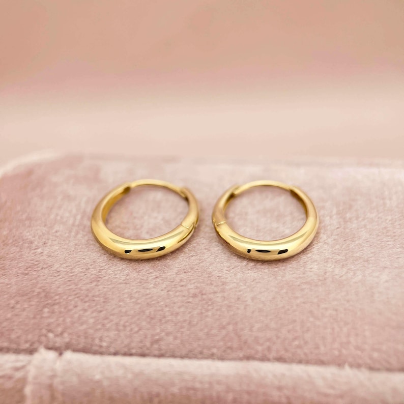 May include: A pair of gold hoop earrings. The earrings are simple and elegant, with a smooth, polished finish.