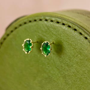 Puede incluir: Un par de pendientes de oro con piedras preciosas verdes ovaladas engastadas en un dise&ntilde;o de filigrana de oro.