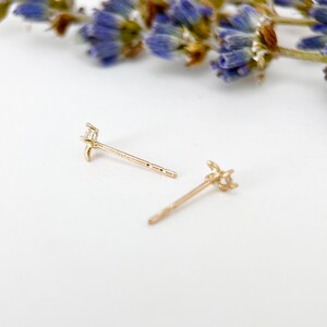 May include: A pair of gold earrings with a small diamond in the centre of each earring. The earrings are in the shape of a crescent moon.