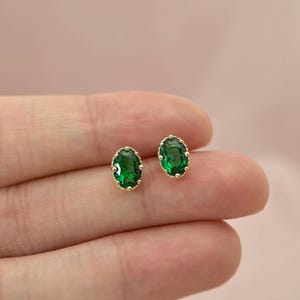 Puede incluir: Un par de pendientes ovalados de oro con piedras preciosas verdes.