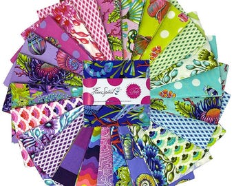 May include: A collection of colorful fabric squares arranged in a circular pattern. The fabrics feature various floral, geometric, and marine-themed designs in shades of pink, purple, blue, and green. The center displays a label with the text "Free Spirit" and "Tula".