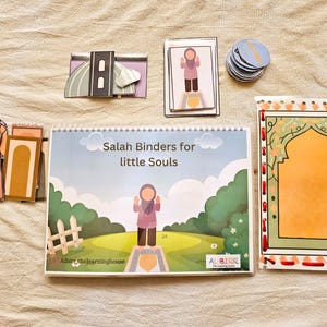 May include: A collection of educational materials for children, including a spiral-bound book titled "Salah Binders for little Souls", prayer mats, and cut-out figures. The items are arranged on a beige fabric surface.