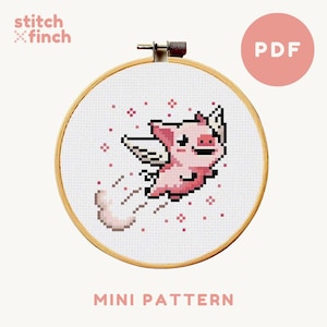 May include: A cross-stitch pattern featuring a pink pig with wings flying through the air. The pattern is in a circular embroidery hoop and is labelled "MINI PATTERN".