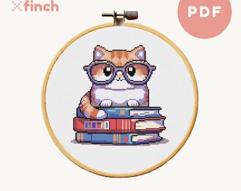 May include: A cross-stitch pattern featuring a cute orange and white cat wearing glasses and sitting on a stack of colorful books. The pattern is in a circular hoop and is ready to be stitched.