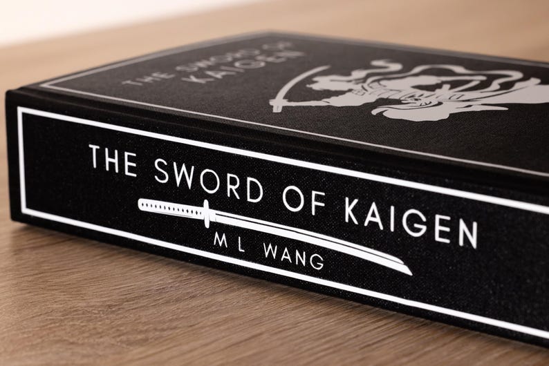 Puede incluir: Un libro negro titulado "The Sword of Kaigen" de M.L. Wang. El t&iacute;tulo y el nombre del autor est&aacute;n en blanco, junto con un gr&aacute;fico de espada estilizado. La portada del libro presenta una ilustraci&oacute;n blanca de una figura con una espada.