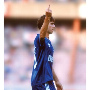 May include: Poster featuring Eric Cantona in a blue jersey, raising his middle finger. The word "CANTONA" is at the bottom. Text includes a quote by Roy Keane and Eric Cantona. The image is a sports-themed artwork.
