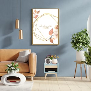 Op de afbeelding: Een ingelijst drukwerk met een gouden geometrisch ontwerp en aquarelbloemelementen. De print bevat de tekst "Wees sterk van hart".