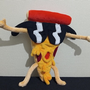 Puede incluir: Un juguete de peluche con forma de porción de pizza que lleva gafas de sol y un sombrero rojo. La pizza tiene una corteza amarilla, salsa roja y queso blanco.