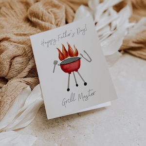 May include: A Father's Day card featuring a watercolour illustration of a red barbecue with flames, a spatula, and tongs. The card reads "Happy Father's Day!" and "Grill Master" in black script.