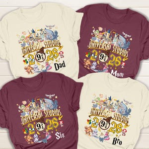 May include: Four t-shirts with a Universal Studios graphic. The design includes the text "Universal Studios 26" with a Hogwarts-themed logo and various cartoon characters. Each shirt has a different family member's name: Dad, Mom, Sis, and Bro.