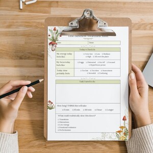 May include: A clipboard with a printed "Time Blindness Awareness Sheet" featuring a mushroom and leaf design. The sheet includes sections for daily check-ins and tasks. A hand holds a pencil, ready to write.