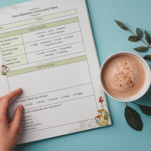 May include: A Time Blindness Awareness Sheet with a hand pointing to the sheet, a cup of coffee, and a sprig of leaves on a blue surface. The sheet has text and boxes for tracking time and feelings. Floral and mushroom illustrations decorate the edges.