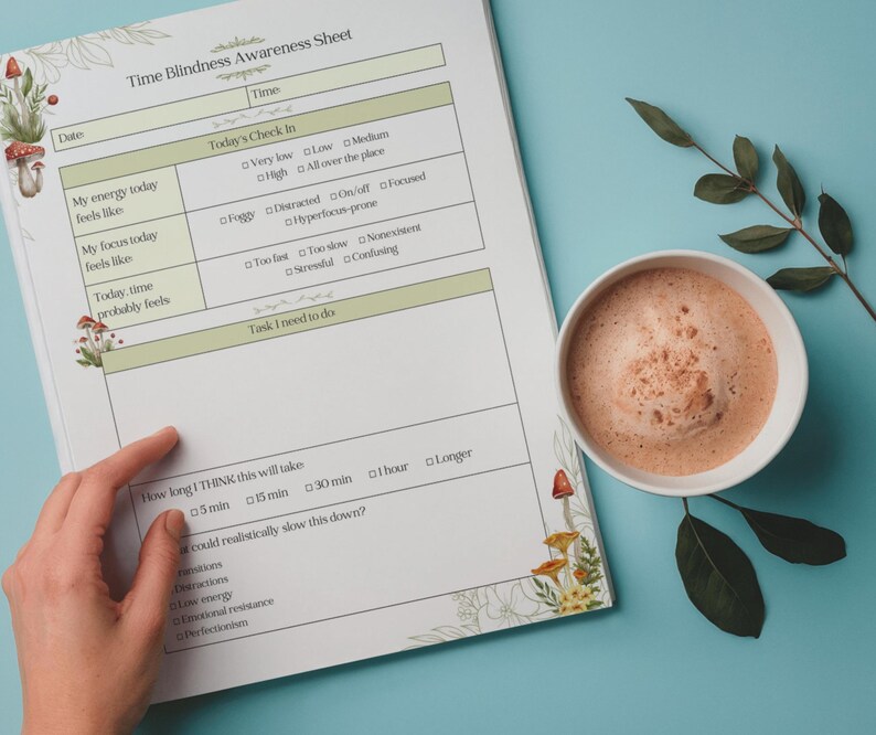May include: A Time Blindness Awareness Sheet with a hand pointing to the sheet, a cup of coffee, and a sprig of leaves on a blue surface. The sheet has text and boxes for tracking time and feelings. Floral and mushroom illustrations decorate the edges.