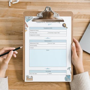 May include: A clipboard with an "Equipment Maintenance Log" form. The form has sections for equipment information, maintenance details, and upcoming tasks. A hand holds a pencil, ready to write on the form. The clipboard is on a wooden surface.