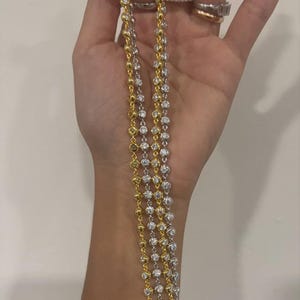 May include: A layered necklace set consisting of one gold-tone chain and one silver-tone chain, both featuring a continuous series of round, clear, faceted stones set in individual metal bezels that create a sparkling, uniform appearance.