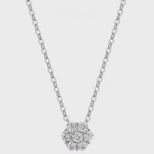 May include: A silver necklace with a cluster pendant of round-cut diamonds. The pendant is a floral design, and the chain is a delicate link style. The necklace is displayed against a plain white background.