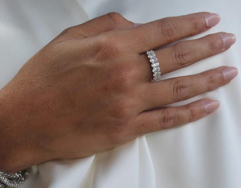 Pu&ograve; includere: Un anello d'argento con pi&ugrave; pietre ovali &egrave; mostrato su una mano. Le pietre dell'anello sono disposte in fila. Lo sfondo &egrave; un tessuto bianco.
