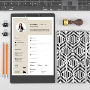 May include: A black and white CV on a clipboard with a photo of a woman, a wooden stamp, and a black and white patterned notebook. The CV includes the name "Korina Villanueva", the title "Graphic Designer", and sections for contact, experience, education, skills, language, and reference.