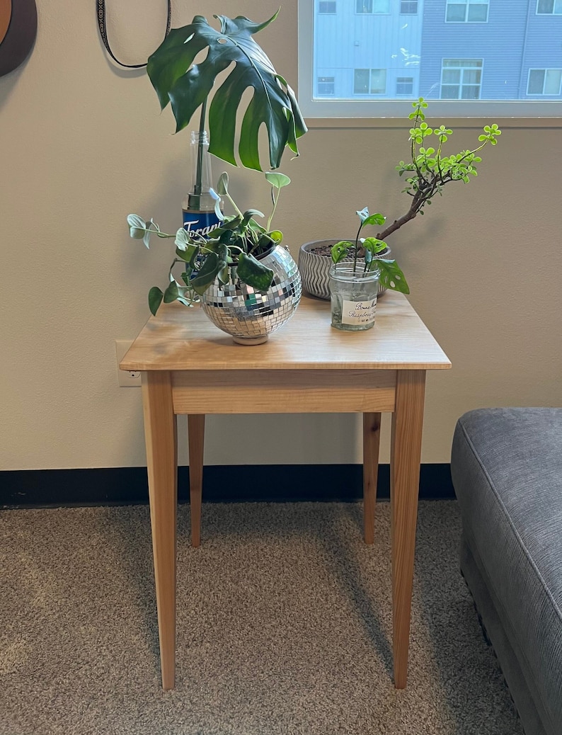 Light colored natural hardwood end / side table with tapered legs and smooth finish.