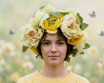 May include: A woman wearing a floral crown made of yellow and cream-colored flowers and green leaves. She is wearing a yellow sweater. Butterflies are in the background.