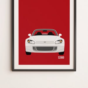 May include: Framed art print featuring a white Honda S2000 sports car against a red background. The car is depicted in a minimalist style with the text "S2000" in the lower right corner. The artwork is in a black frame.