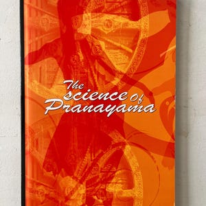 May include: A book titled "The Science of Pranayama" with a vibrant orange cover. The cover features a silhouette of a person in a yoga pose and decorative patterns. The author's name, Sri Swami Sivananda, is printed at the bottom.