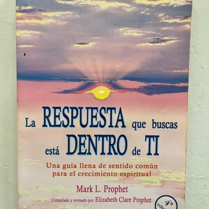 May include: A paperback book with a sunset sky background. The title "La RESPUESTA que buscas está DENTRO de TI" is displayed in large blue letters. The author's name, Mark L. Prophet, is also visible. The book is a guide for spiritual growth.