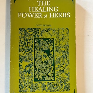 May include: A vintage book titled "The Healing Power of Herbs" by May Bethel. The cover is a light green with dark green botanical illustrations and text. The book's title is in large, bold white letters.
