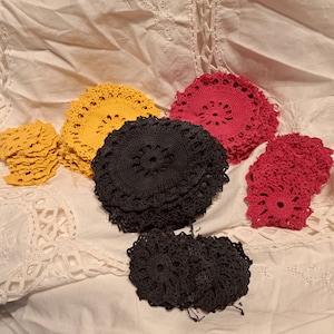 Könnte beinhalten: Eine Sammlung gehäkelter Deckchen in Gelb, Rot und Schwarz. Die Deckchen sind übereinander gestapelt und in einem Kreis angeordnet.