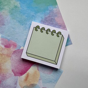 May include: A light green notepad with a black outline and a spiral binding. The spiral binding is made of green circles.