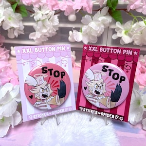 Puede incluir: Dos pines de botón XXL con un personaje de dibujos animados y la palabra "STOP". Los pines son rosas y rojos con "XXL BUTTON PIN" en la parte superior. El personaje tiene una expresión severa y viste un uniforme blanco.