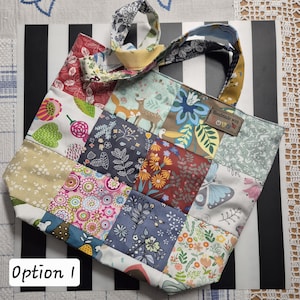 Könnte beinhalten: Eine Patchwork-Tragetasche mit einer Vielzahl von Stoffquadraten mit Blumen- und Naturmotiven. Die Tasche hat einen Griff aus passendem Stoff und ein kleines Etikett mit der Aufschrift "Handmade with love". Der Text "Option 1" ist unten sichtbar.