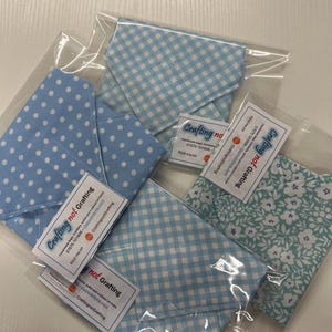 Op de afbeelding: Verschillende stoffen zakjes in transparante verpakking. De zakjes hebben verschillende lichtblauwe patronen, waaronder stippen, ruitjes en bloemmotieven. Elk zakje heeft een klein label met de tekst "Crafting not Grafting".
