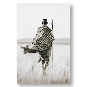 May include: A person wearing a plaid blanket walks through a field of tall grass, holding a spear in their right hand.