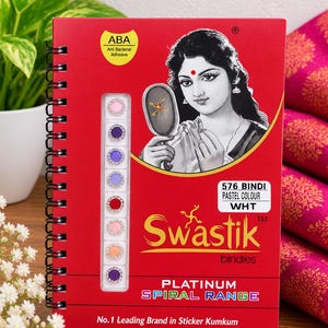 May include: A red spiral-bound display card featuring a graphic of a person holding a mirror and a vertical strip of eight circular bindis in various pastel and solid colors. The text reads Swastik Platinum Spiral Range and 576 Bindi.