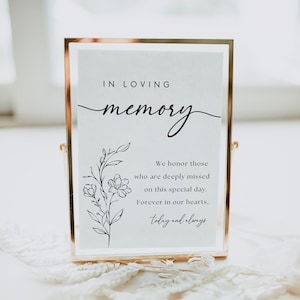 Puede incluir: Un cartel blanco en un marco dorado con el texto "IN LOVING memory" y un diseño floral. El cartel dice "Honramos a quienes se extrañan profundamente en este día especial. Por siempre en nuestros corazones, hoy y siempre."