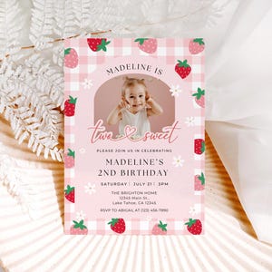 Puede incluir: Una tarjeta de invitación de cumpleaños rectangular con un patrón de cuadros vichy rosa y blanco, ilustraciones de fresas y margaritas. Incluye un marco de fotos central arqueado, el texto "Madeline is two sweet" y detalles del 2º cumpleaños.