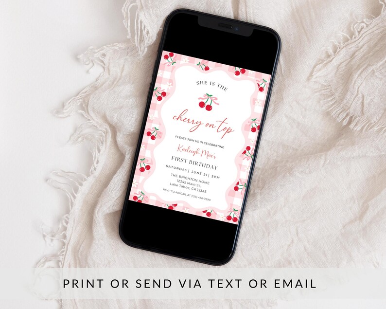 May include: A smartphone displaying a digital invitation with a pink and white gingham background, red cherry illustrations, and text that reads: SHE IS THE cherry on top, PLEASE JOIN US IN CELEBRATING, Kaeleigh Mae's, FIRST BIRTHDAY, SATURDAY, JUNE 27 | 2PM.