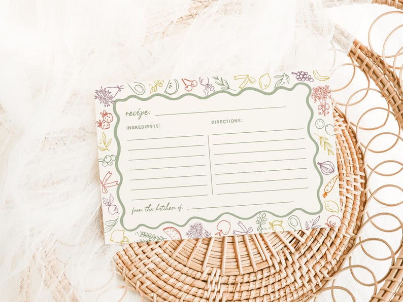 May include: A blank recipe card with a green border and a colourful illustration of fruits and vegetables. The card has the words "recipe", "ingredients", "directions", and "from the kitchen of" printed on it.
