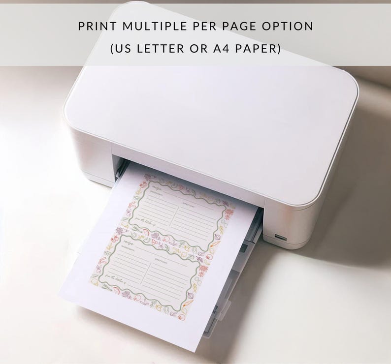 May include: A white printer with a sheet of paper emerging from the tray. The paper features two recipe cards printed on it, each with a colourful floral border. The text on the paper reads "Print Multiple Per Page Option (US Letter or A4 Paper)".