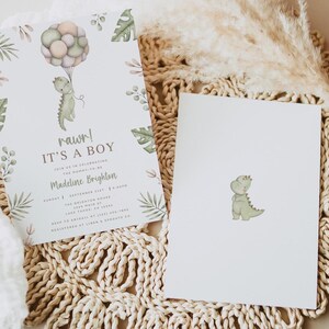 Op de afbeelding: Een witte uitnodigingskaart en een bijpassende blanco kaart met een aquarel groene dinosaurus die een tros pastelkleurige ballonnen vasthoudt. De uitnodiging bevat de tekst rawr! IT'S A BOY, JOIN US IN CELEBRATING THE MOMMY-TO-BE, Madeline Brighton, en evenementdetails.