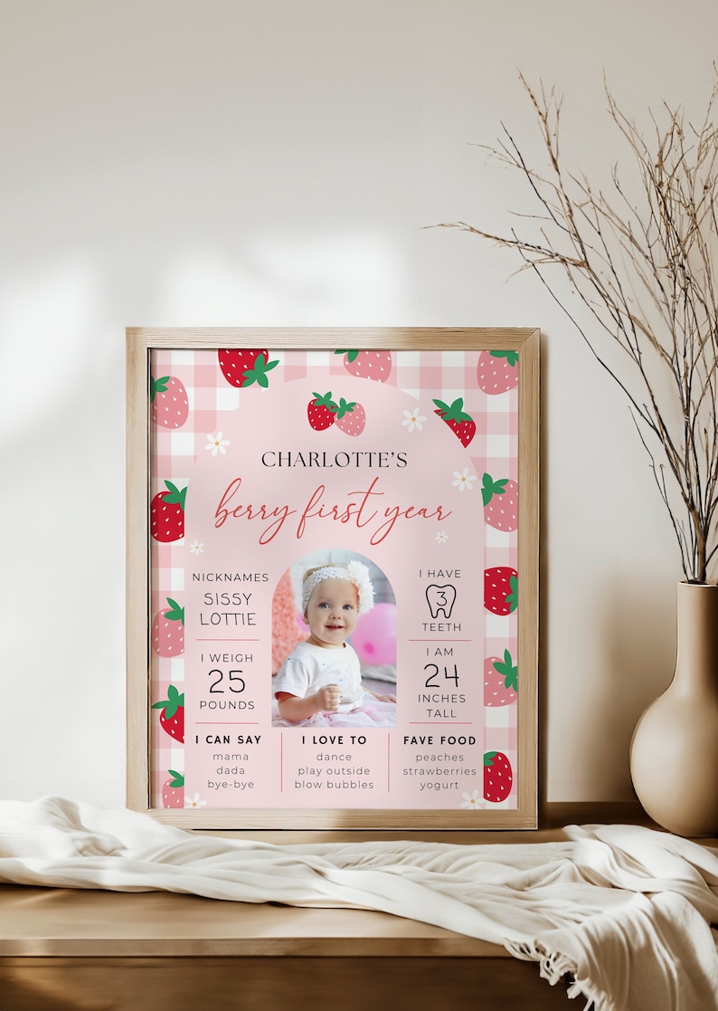 Pictures shows 16x20” framed berry first birthday milestone poster sitting on a table.