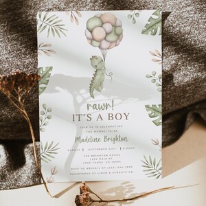 Op de afbeelding: Een witte uitnodigingskaart voor een babyshower met een aquarelillustratie van een groene dinosaurus die een tros pastelkleurige ballonnen vasthoudt. De tekst luidt rawr! IT'S A BOY, JOIN US IN CELEBRATING THE MOMMY-TO-BE, Madeline Brighton en evenementdetails.
