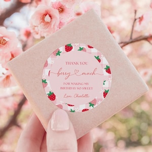 May include: Pink and white gingham patterned circle sticker with red strawberries and white flowers. The sticker says "Thank you berry much for making my birthday so sweet. Love, Charlotte."