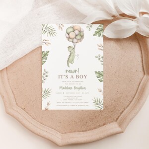 Op de afbeelding: Een rechthoekige uitnodigingskaart voor een babyshower met een aquarelillustratie van een groene dinosaurus die een bos pastelkleurige ballonnen vasthoudt. De tekst luidt: rawr! IT'S A BOY, JOIN US IN CELEBRATING THE MOMMY-TO-BE, Madeline Brighton, en de evenementdetails.