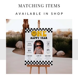 May include: A yellow and black birthday sign featuring a smiling face and the text "One Happy Year". The sign also includes details about the child's age, weight, height, and favourite foods.